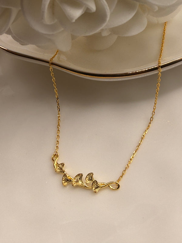 Gold necklace with floral design on a beige surface