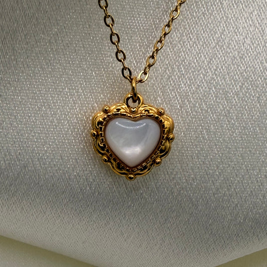Heart-shaped pendant with gold frame on a light gray background
