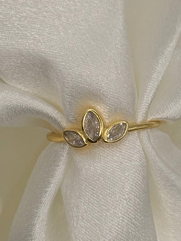 Gold ring with three stones on a white fabric background
