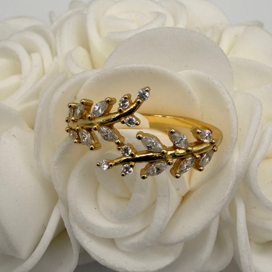 Gold ring with diamond-like stones on a white floral background