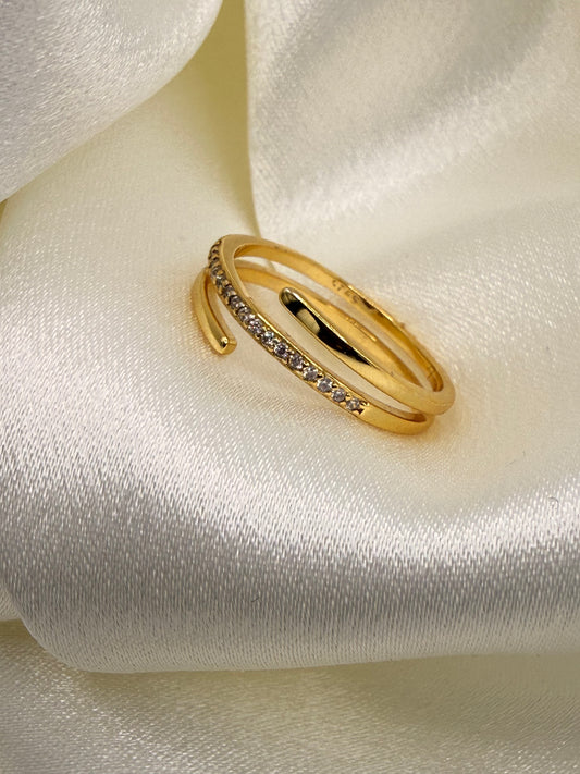 Gold ring with embedded stones on a white fabric background